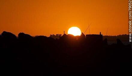 Silhouette of fishermen with the sun disappearing below the horizon - Department of Montevideo - URUGUAY. Photo #79052