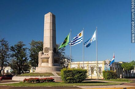 Obelisco y banderas locales e internacionales en la plaza Batlle y Ordóñez - Departamento de Artigas - URUGUAY. Foto No. 83680