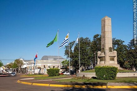 Obelisco y banderas locales e internacionales en la plaza Batlle y Ordóñez - Departamento de Artigas - URUGUAY. Foto No. 83667