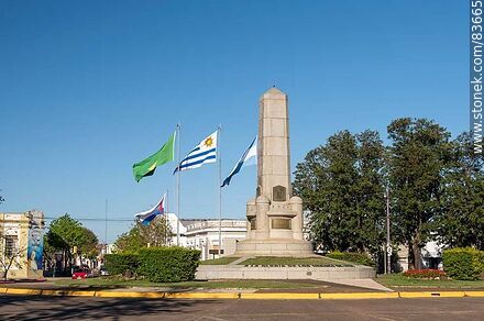 Obelisco y banderas locales e internacionales en la plaza Batlle y Ordóñez - Departamento de Artigas - URUGUAY. Foto No. 83665