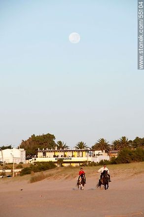 Jinetes cabalgando en la playa al amanecer con luna llena - Departamento de Maldonado - URUGUAY. Foto No. 55104