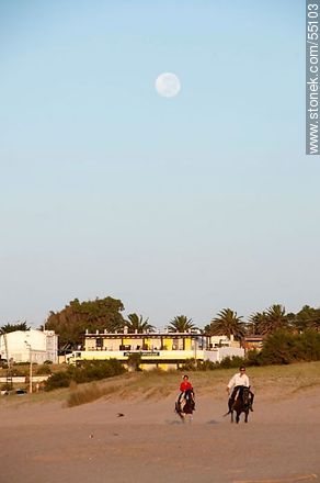 Jinetes cabalgando en la playa al amanecer con luna llena - Departamento de Maldonado - URUGUAY. Foto No. 55103