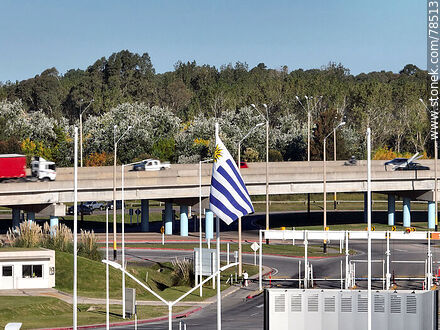 Vista aérea de la bandera uruguaya con fondo el acceso elevado de las rutas 101 e Interbalnearia - Departamento de Canelones - URUGUAY. Foto No. 78513