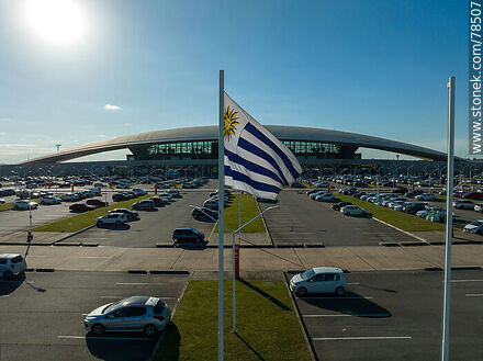 Vista aérea de la bandera uruguaya flameando frente al estacionamiento del aeropuerto - Departamento de Canelones - URUGUAY. Foto No. 78507
