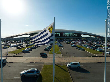 Vista aérea de la bandera uruguaya flameando frente al estacionamiento del aeropuerto - Departamento de Canelones - URUGUAY. Foto No. 78506