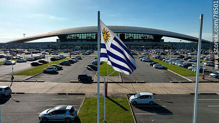 Vista aérea de la bandera uruguaya flameando frente al estacionamiento del aeropuerto - Departamento de Canelones - URUGUAY. Foto No. 78501