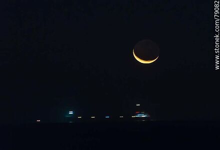 The new moon about to set in the sea and the lights of a moving ship -  - MORE IMAGES. Photo #79082