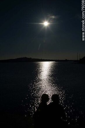 Silueta de una pareja sentada en la escollera Sarandí en contraste con el reflejo del sol en el río -  - IMÁGENES VARIAS. Foto No. 79208