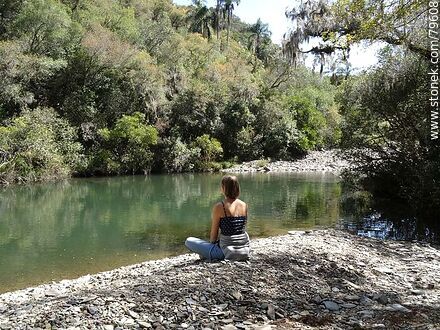 Woman meditating on the shore of Yerbal Chico stream - Department of Treinta y Tres - URUGUAY. Photo #79608