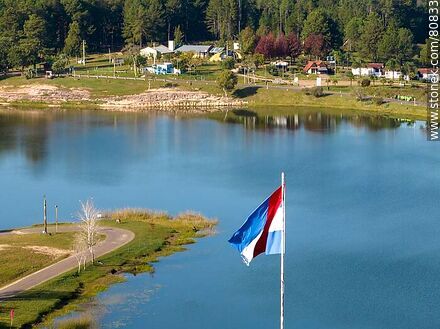 Vista aérea de la bandera de Artigas con fondo el primer lago y cabañas - Departamento de Tacuarembó - URUGUAY. Foto No. 80833