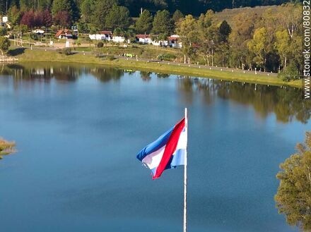 Vista aérea de la bandera de Artigas con fondo el primer lago y cabañas - Departamento de Tacuarembó - URUGUAY. Foto No. 80832