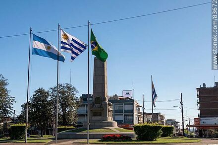 Obelisco y banderas locales e internacionales en la plaza Batlle y Ordóñez - Departamento de Artigas - URUGUAY. Foto No. 83672