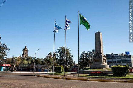 Obelisco y banderas locales e internacionales en la plaza Batlle y Ordóñez - Departamento de Artigas - URUGUAY. Foto No. 83671