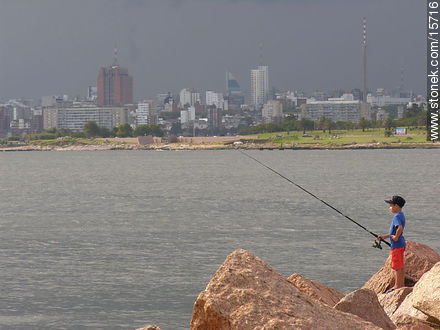 Niño pescador. Al fondo el barrio Sur - Departamento de Montevideo - URUGUAY. Foto No. 15716